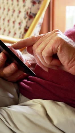 Älterer-Mann-Mit-Tablet-PC,-Während-Er-Im-Schaukelstuhl-Sitzt