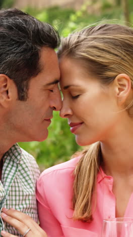 Couple-romancing-while-having-a-glass-of-wine-in-field