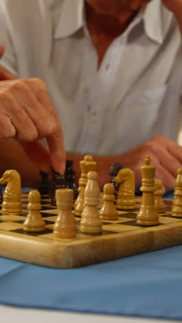 Mid-section-of-senior-friends-playing-chess