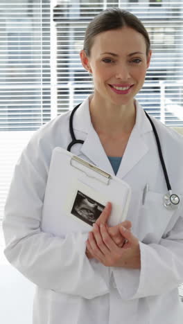 Doctor-leaning-on-desk-smiling-at-camera