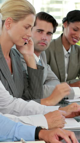 Business-team-taking-notes-during-conference-while-colleague-having-a-phone-call