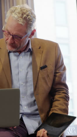 Businessman-and-coworkers-discussing-over-laptop-at-desk