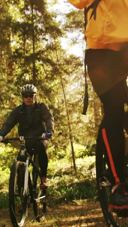 Mountain-biking-couple-riding-in-the-forest-on-a-sunny-day