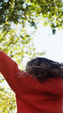 Girl-outdoors-turning-and-holding-up-hands