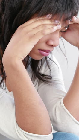 Stressed-woman-holding-her-head-on-couch-