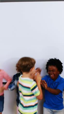 Schoolteacher-and-kids-giving-high-five-in-classroom