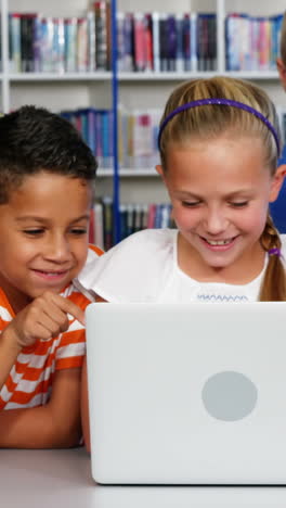 Niños-De-La-Escuela-Usando-Una-Computadora-Portátil-En-La-Biblioteca