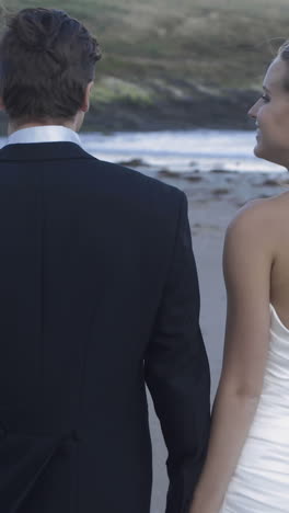 Smiling-newlyweds-walking-on-the-beach