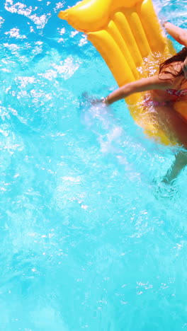 Overhead-of-brunette-sitting-on-lilo-in-pool-on-sunny-day