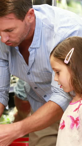 Father-and-daughter-picking-out-salad-in-supermarket