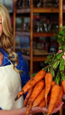 Smiling-staff-holding-bunch-of-carrots-in-organic-section