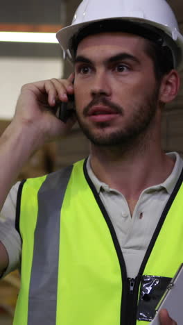 Warehouse-worker-talking-on-the-phone-holding-clipboard