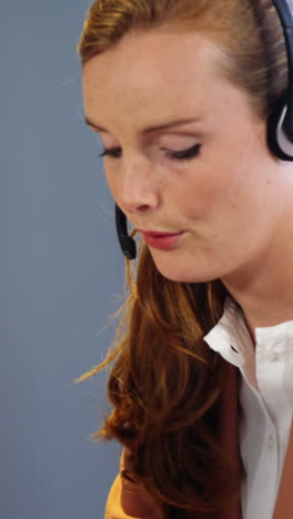 Businesswoman-talking-on-a-headset-at-desk