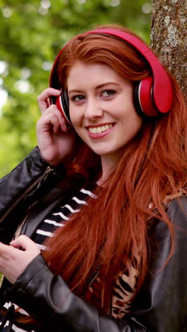 Pretty-redhead-listening-to-music-in-the-park-