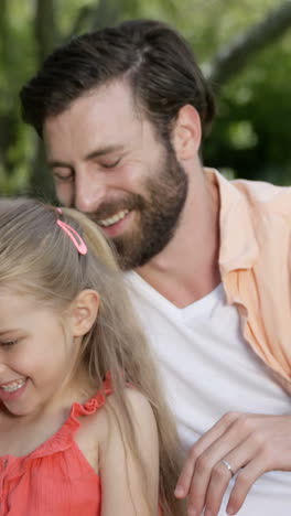 Süße-Familie-Sitzt-Auf-Dem-Gras-Und-Schaut-Auf-Ein-Smartphone