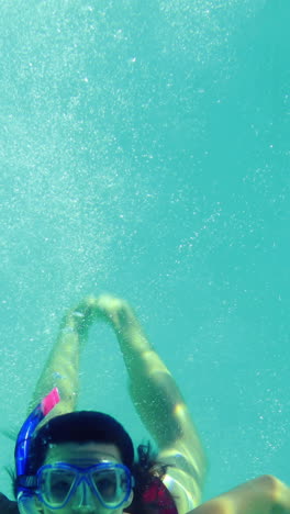 Pretty-brunette-diving-into-swimming-pool-wearing-snorkel