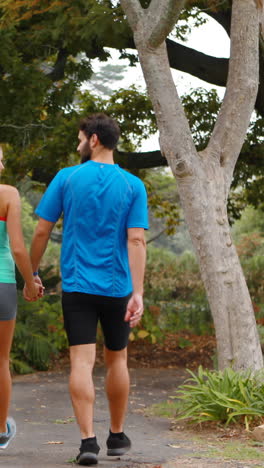 Rear-view-of-couple-holding-hands-while-walking