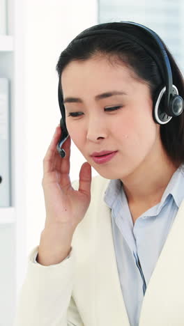 Asian-businesswoman-using-headset-and-laptop