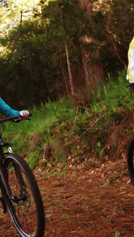 Mountain-biking-couple-riding-in-the-forest-on-a-sunny-day