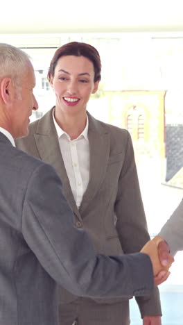 Business-people-shaking-hands-and-smiling-