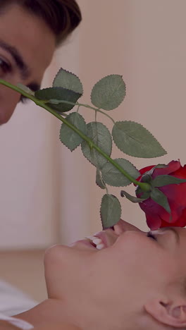 Man-tickling-his-girlfriend-with-a-red-rose-on-bed