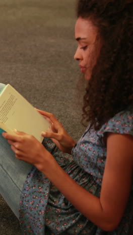 Focused-student-reading-a-book-lying--on-the-floor-