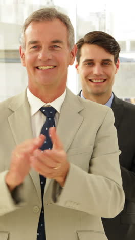 Business-team-smiling-at-camera-and-clapping