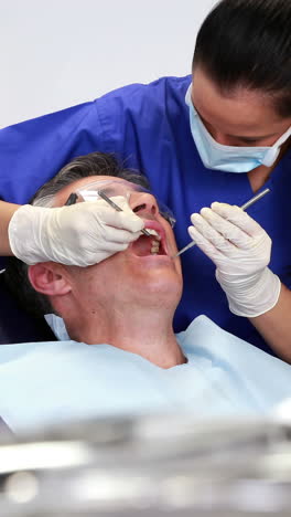 Dentist-examining-a-patients-teeth-in-the-dentists-chair