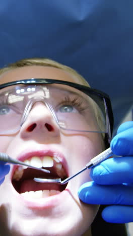 Dentist-examining-a-young-patient-with-tool