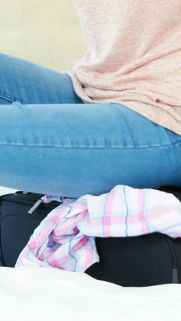 Woman-sitting-on-her-luggage