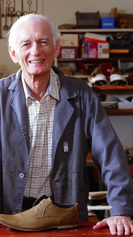 Portrait-of-smiling-shoemaker-standing-in-workshop