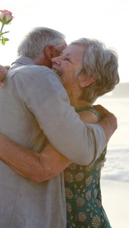 Pareja-De-Ancianos-Jubilados-Abrazándose-Mientras-Sostienen-Una-Flor