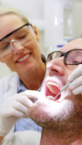 Dentista-Femenina-Examinando-A-Un-Paciente-Masculino-Con-Herramientas