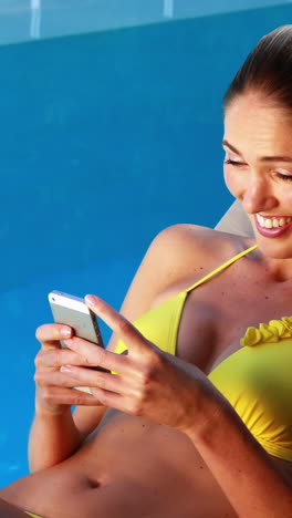 Hermosa-Rubia-En-Bikini-Enviando-Mensajes-De-Texto-Por-Teléfono-Junto-A-La-Piscina