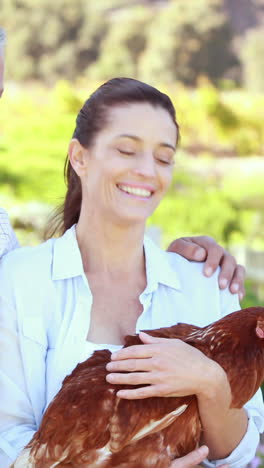 Smiling-farmer-couple-holding-chickens