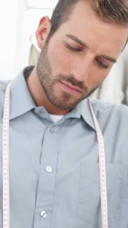 Handsome-fashion-designer-sketching-at-his-desk-