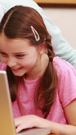 Teacher-helping-pupil-with-laptop