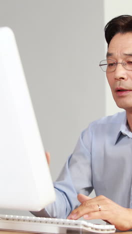 Asian-businessman-using-computer-at-desk