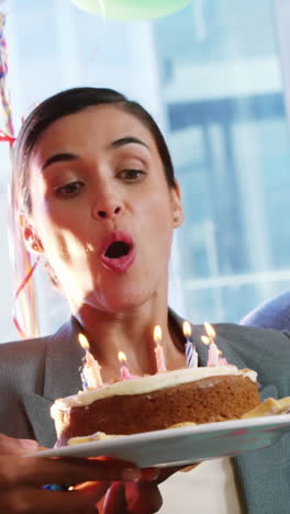 Businesswoman-blowing-birthday-candles-with-colleagues