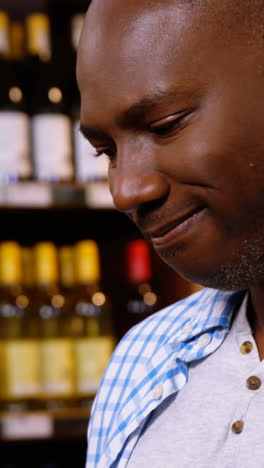 Man-looking-at-wine-bottle-in-grocery-section