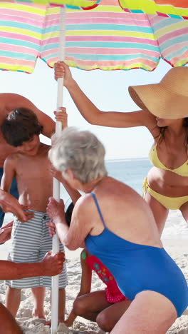 Three-smiling-generation-family-setting-up-sun-umbrella