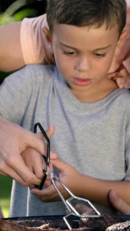 Close-up-on-a-father-is-teaching-to-his-son-to-do-a-barbecue