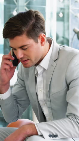 Businessman-picking-up-a-call-while-working-in-laptop