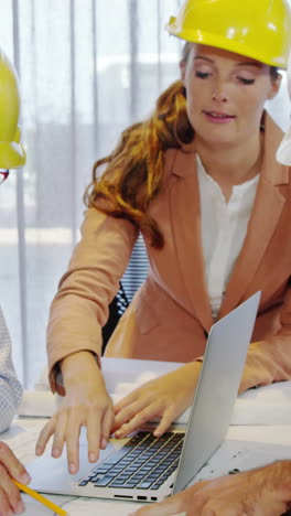 Businesswoman-and-coworkers-discussing-blueprint