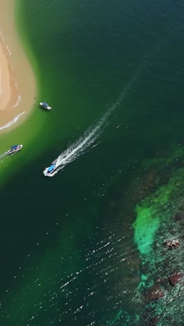 Sailing-through-Cacaluta-Bay-in-Bahias-de-Huatulco,-vertical-aerial-view