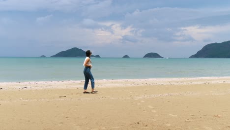 Into-and-out-frame-young-woman-walking,-secluded-tranquil-island-beach