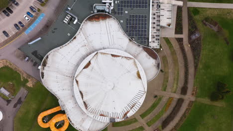 Solar-panels-on-top-of-commercial-water-park-and-hotel-building,-aerial-top-down-view