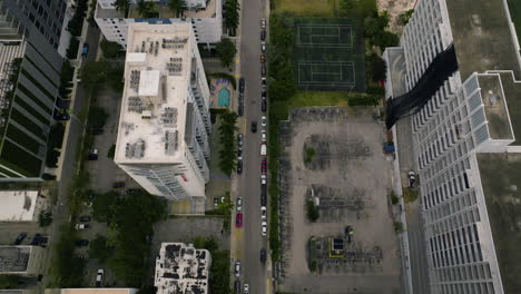 Aerial-view-tilting-over-a-car-driving-in-middle-of-buildings-in-Edgewater,-Miami