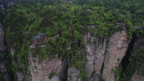 Aerial-panning-shot-of-tourists-exploring-scenic-walkways-atop-lush,-towering-cliffs-in-Zhangjiajie-National-Forest-Park,-China