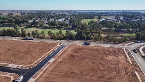 Aerial-flyover-of-new-residential-construction-stage-and-golf-course-and-lake-beyond